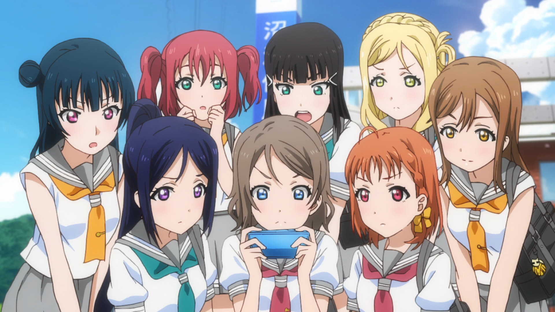 The girls of Aqours gather around a smart phone to check out the school idol rankings in a scene from the Love Live! Sunshine !! TV anime.
